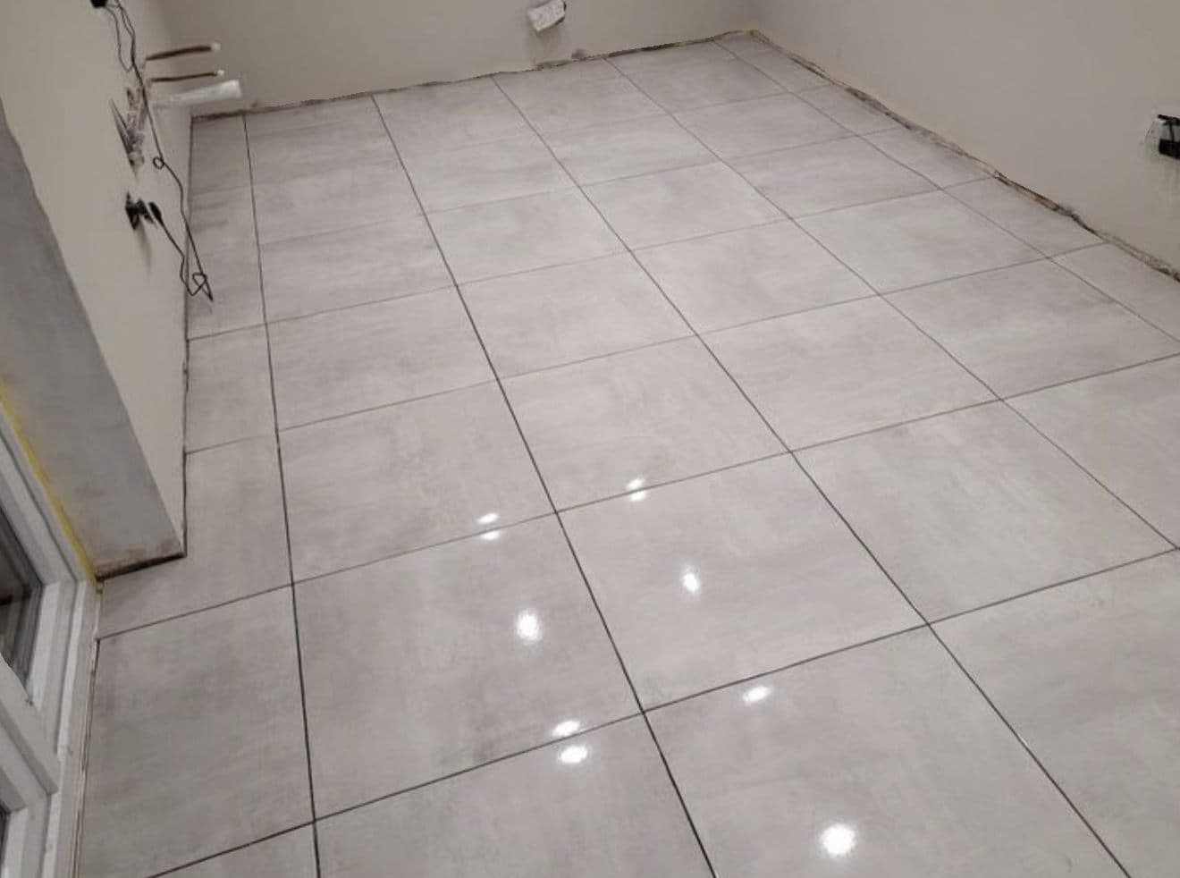 Large-format grey porcelain tiles laid across a bathroom floor before the suite goes in