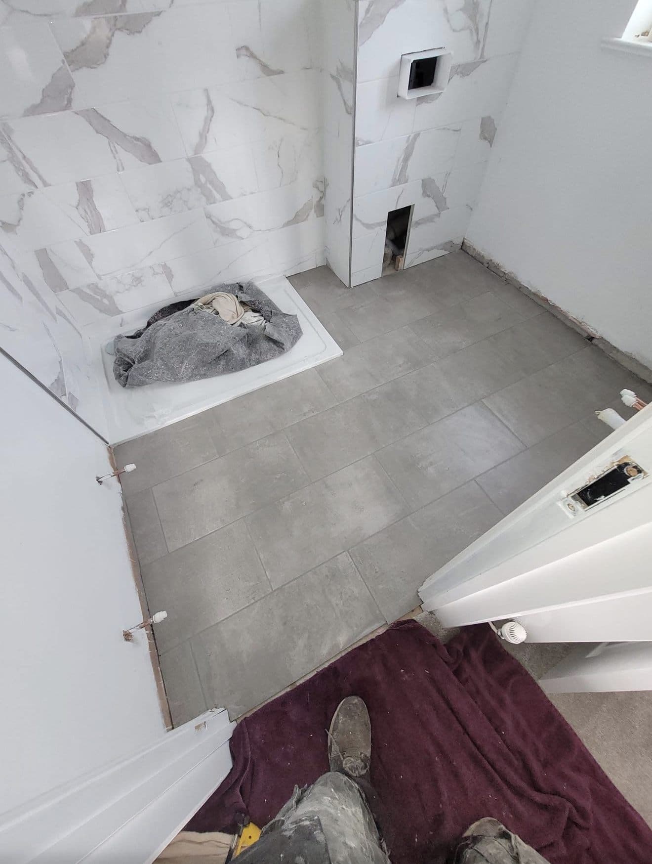 Marble-effect wall tiles and grey floor tiles in place during a bathroom refit