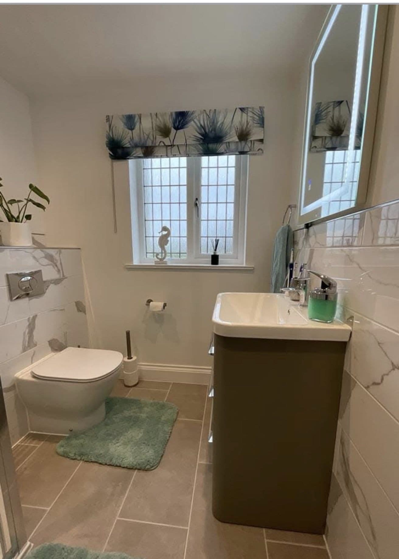 Finished bathroom with a vanity basin unit, wall-hung toilet and marble-effect tiling