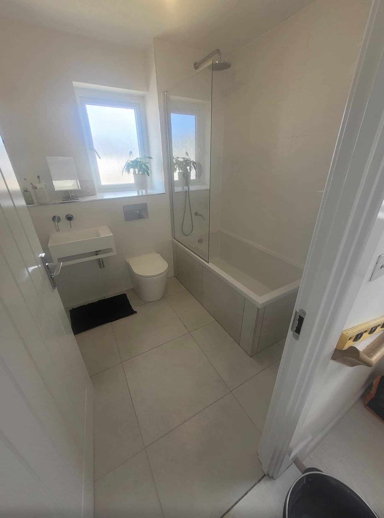 Finished small bathroom with bath and shower screen, wall-hung basin and back-to-wall toilet