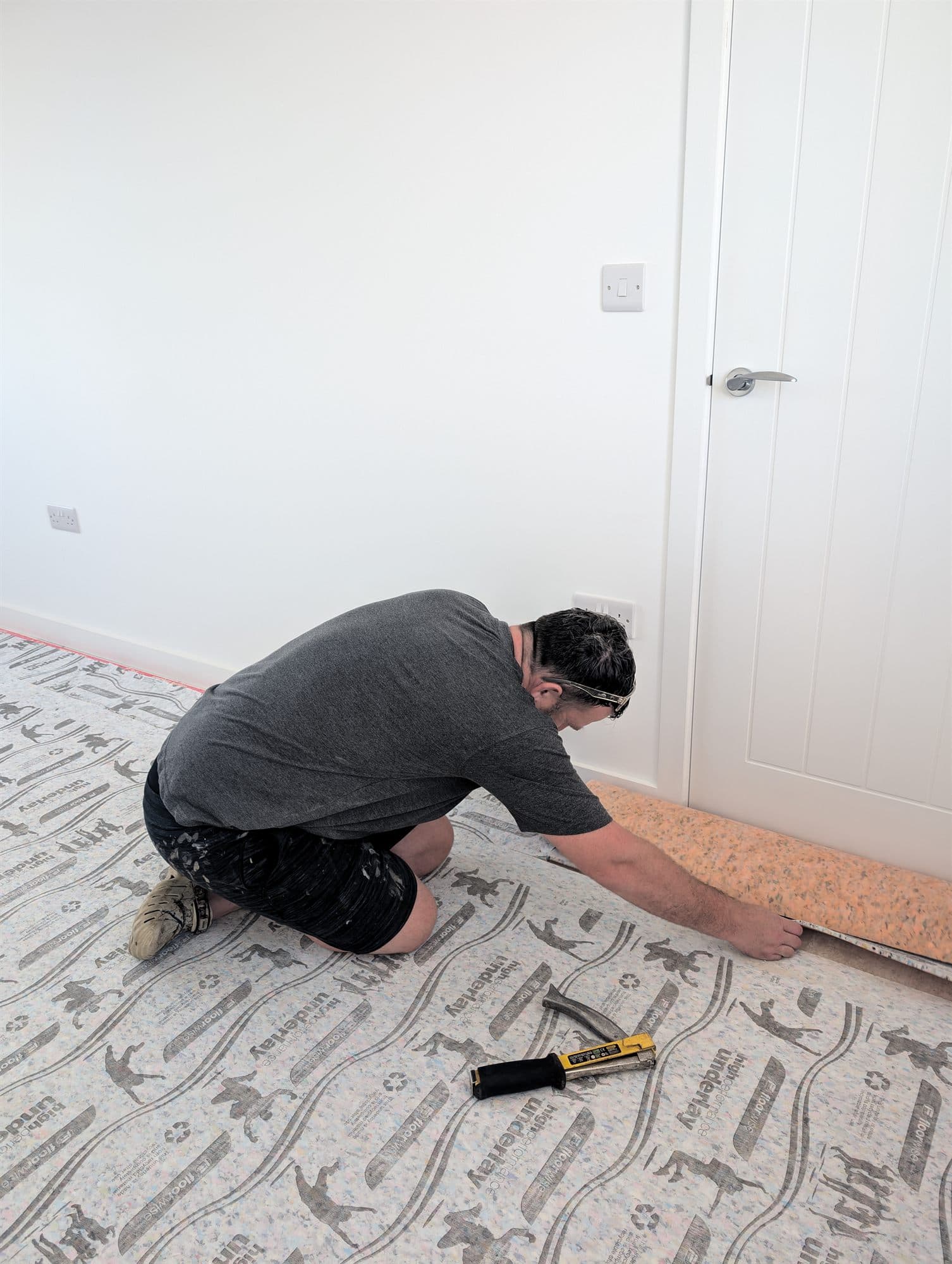Carpet being fitted over new underlay in a bedroom