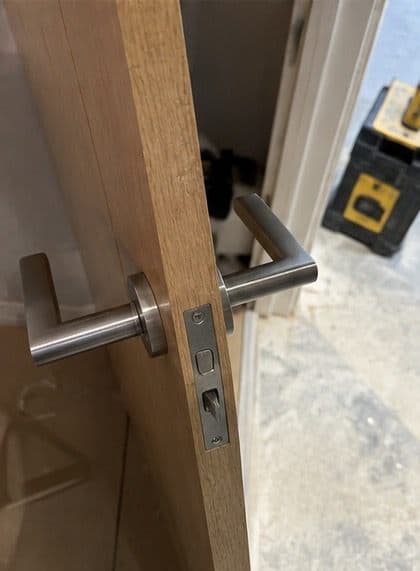 Brushed steel lever handle and latch fitted to a wooden door