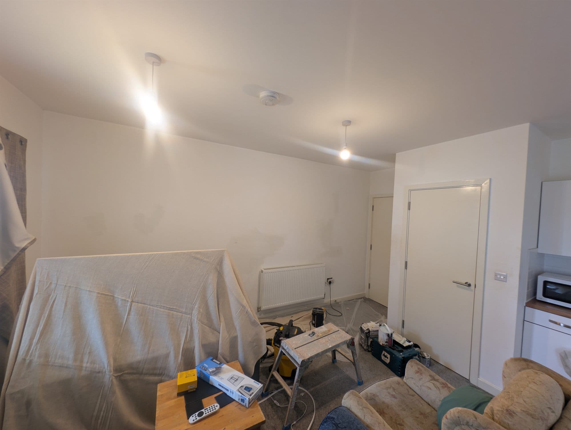 Living room with furniture covered in dust sheets ready for decorating
