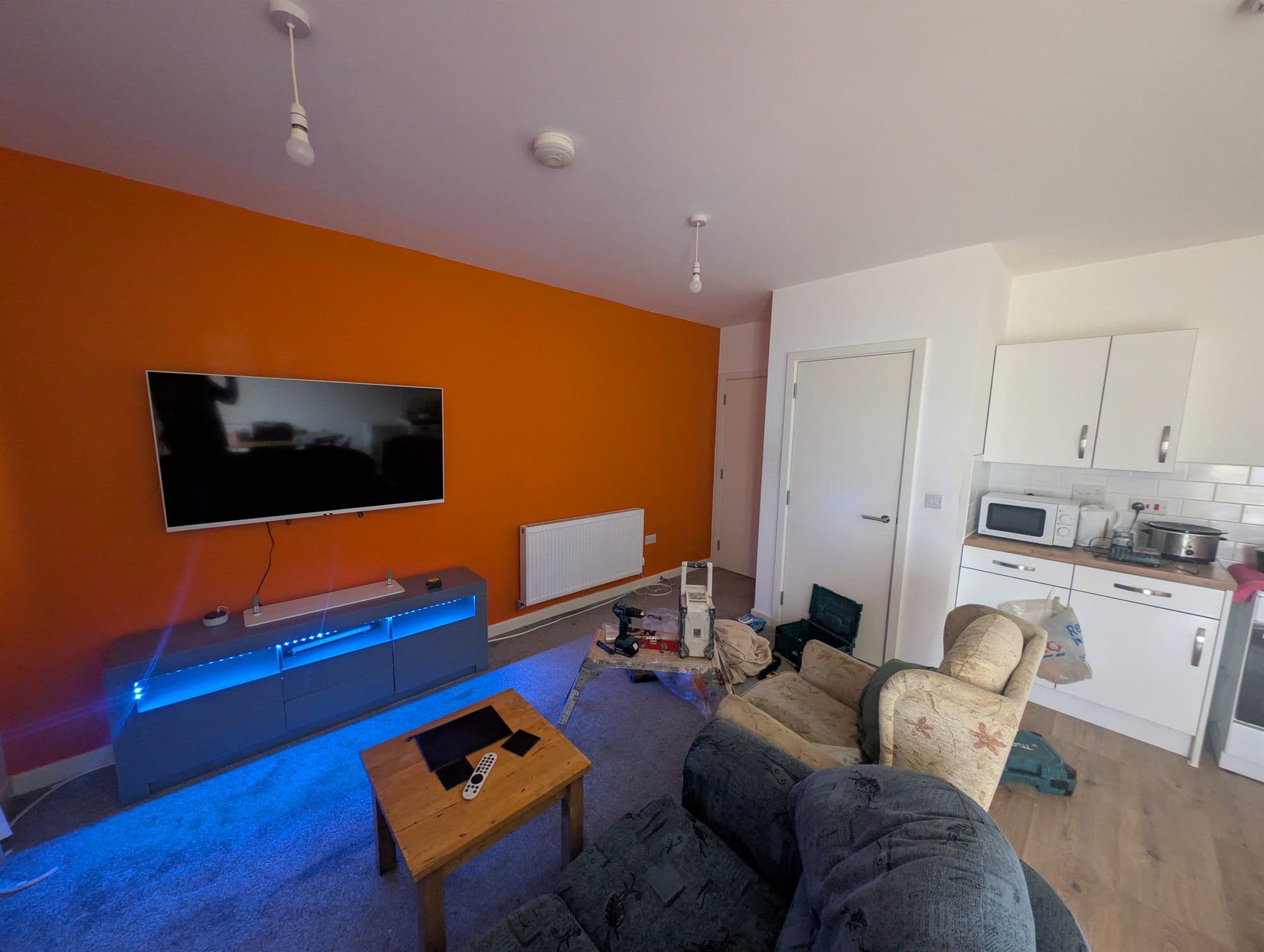 Living room with a freshly painted orange feature wall behind the television