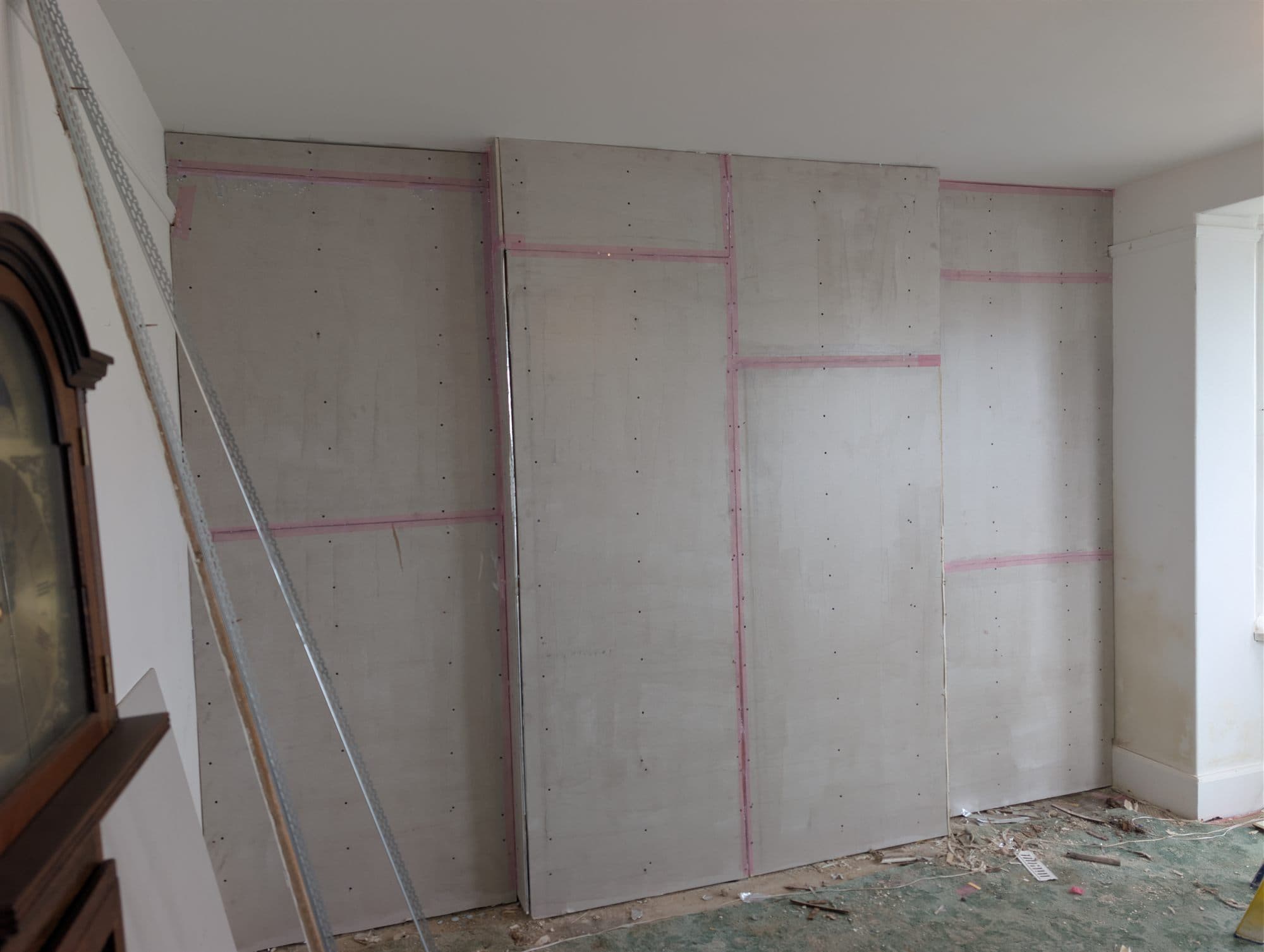 Wall newly boarded with plasterboard and scrim tape over the joints, ready for skimming