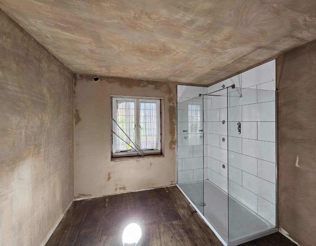 Bathroom with a newly installed tiled shower enclosure, walls and ceiling freshly plastered