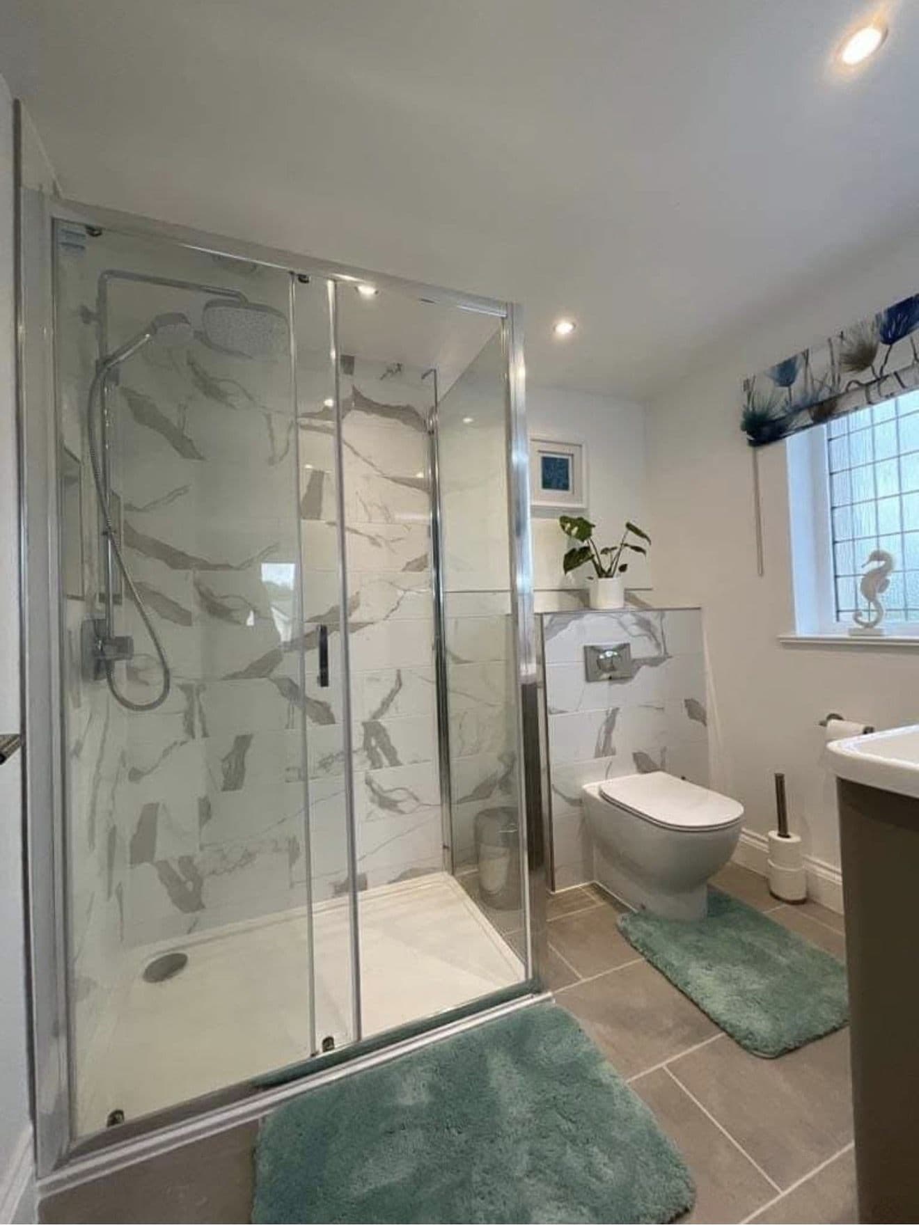 Finished bathroom with a walk-in shower, marble-effect tiled walls and grey floor tiles
