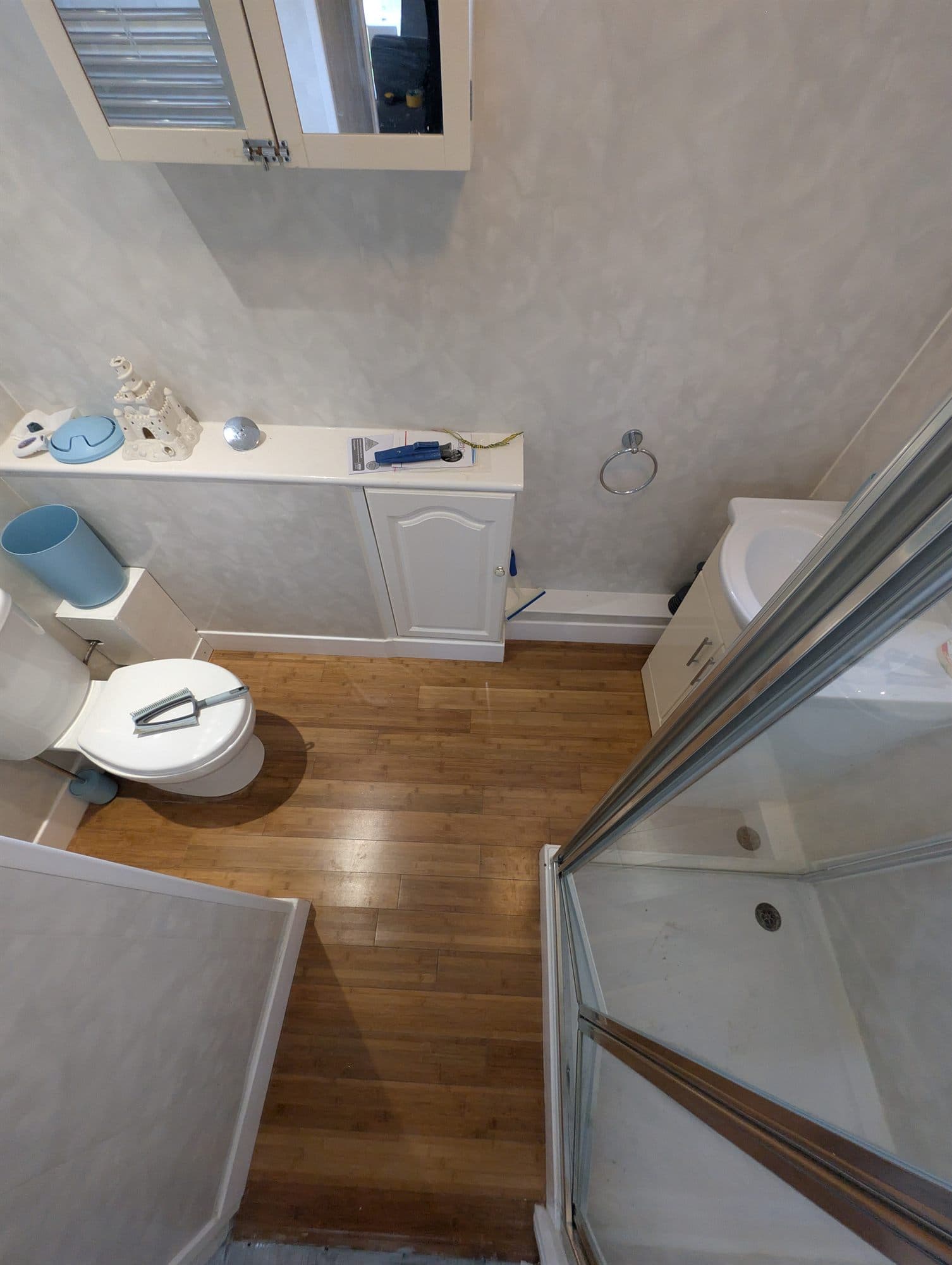 Bathroom with worn wood-effect floor before replacement