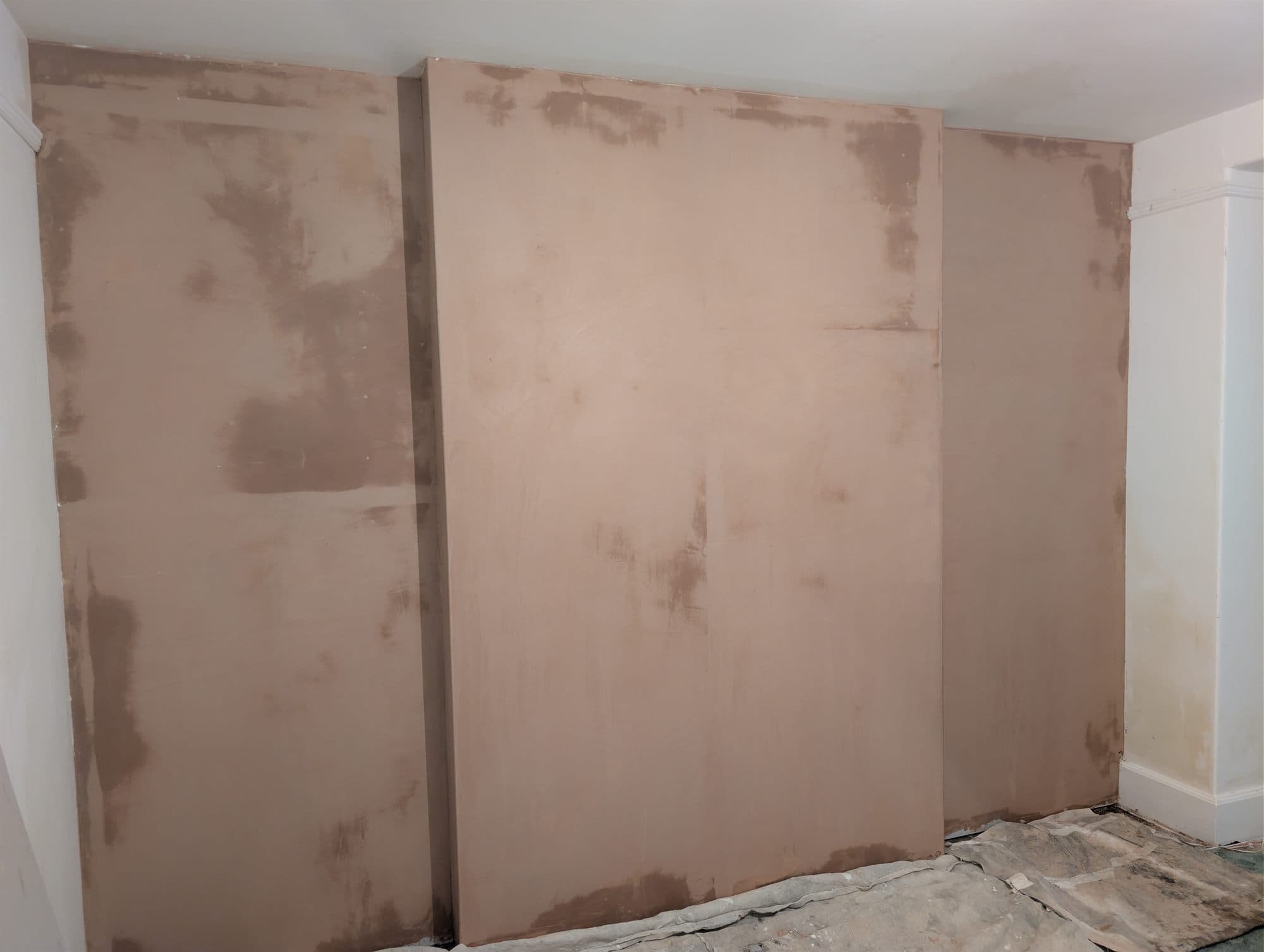 Freshly skimmed plaster wall drying, showing the pink finish coat