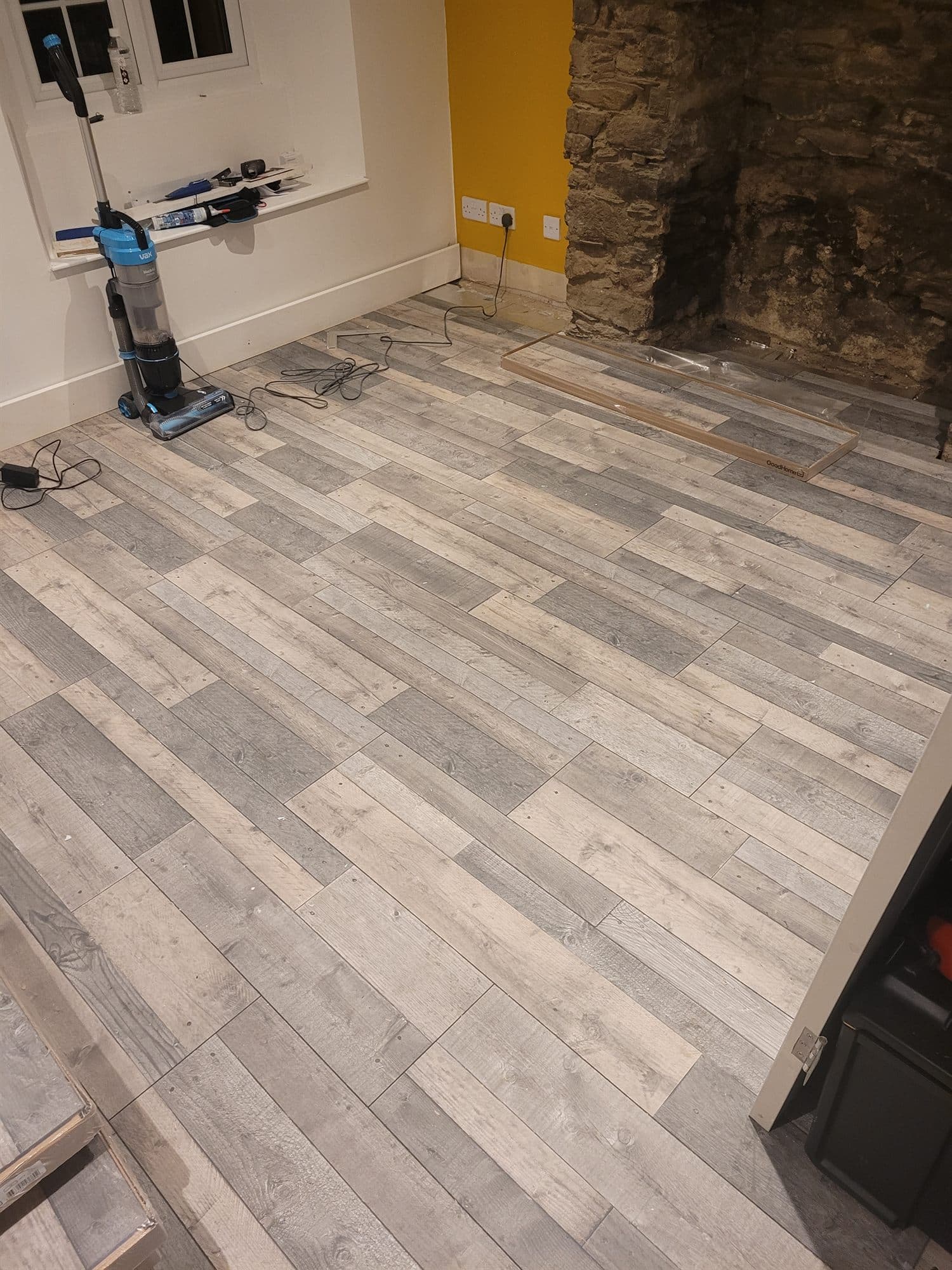 Grey wood-effect flooring laid in a room with a stone fireplace