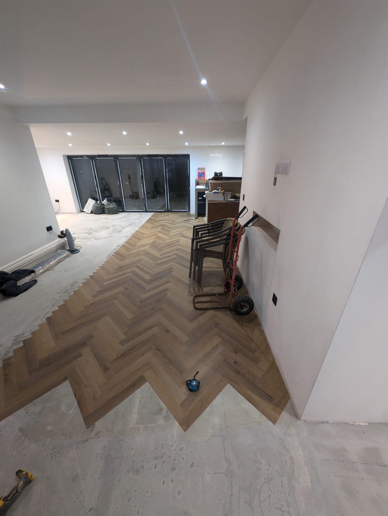 Herringbone floor running the length of an open-plan room towards bi-fold doors