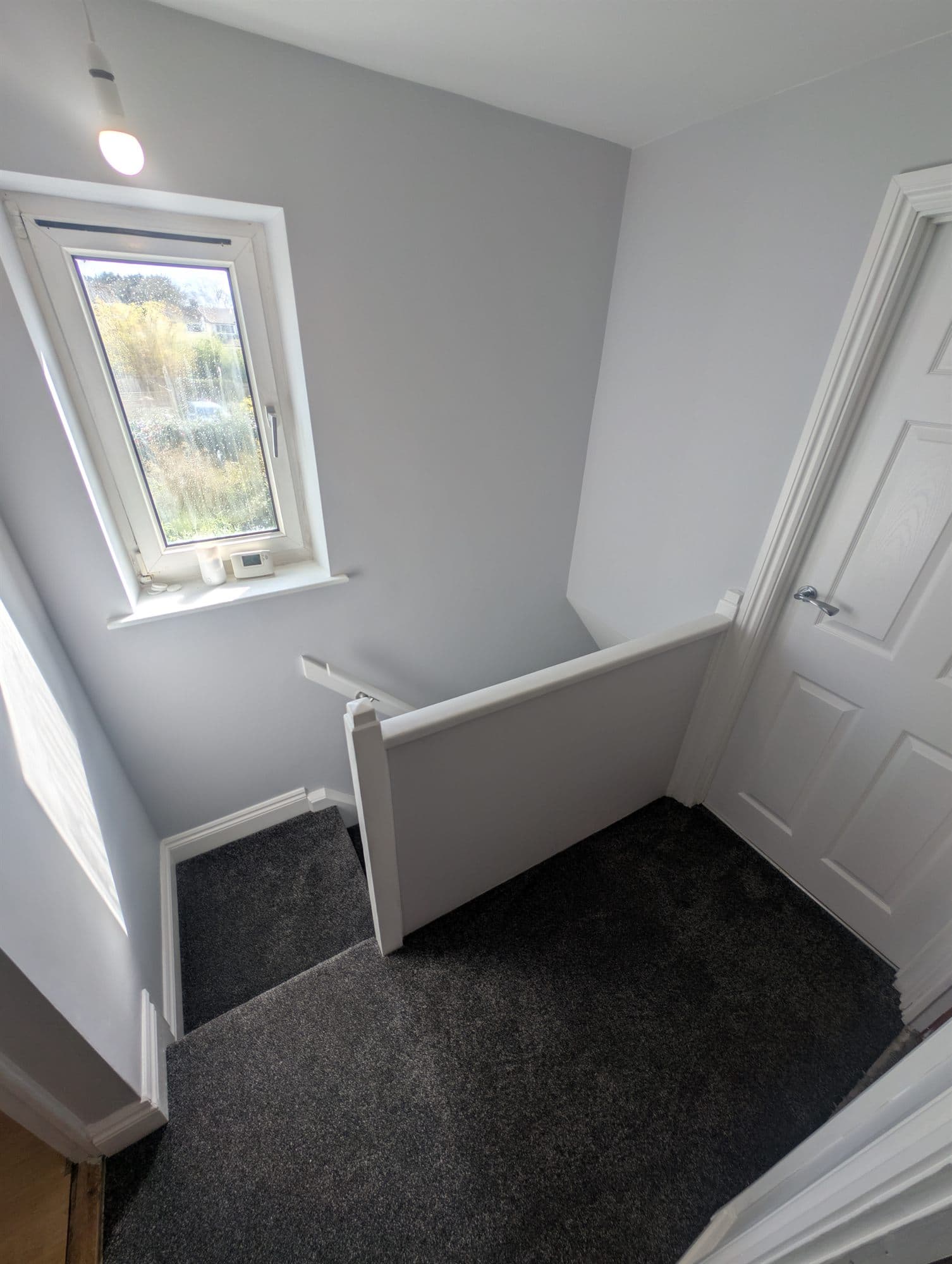 Landing finished with light grey walls, white woodwork and dark grey carpet