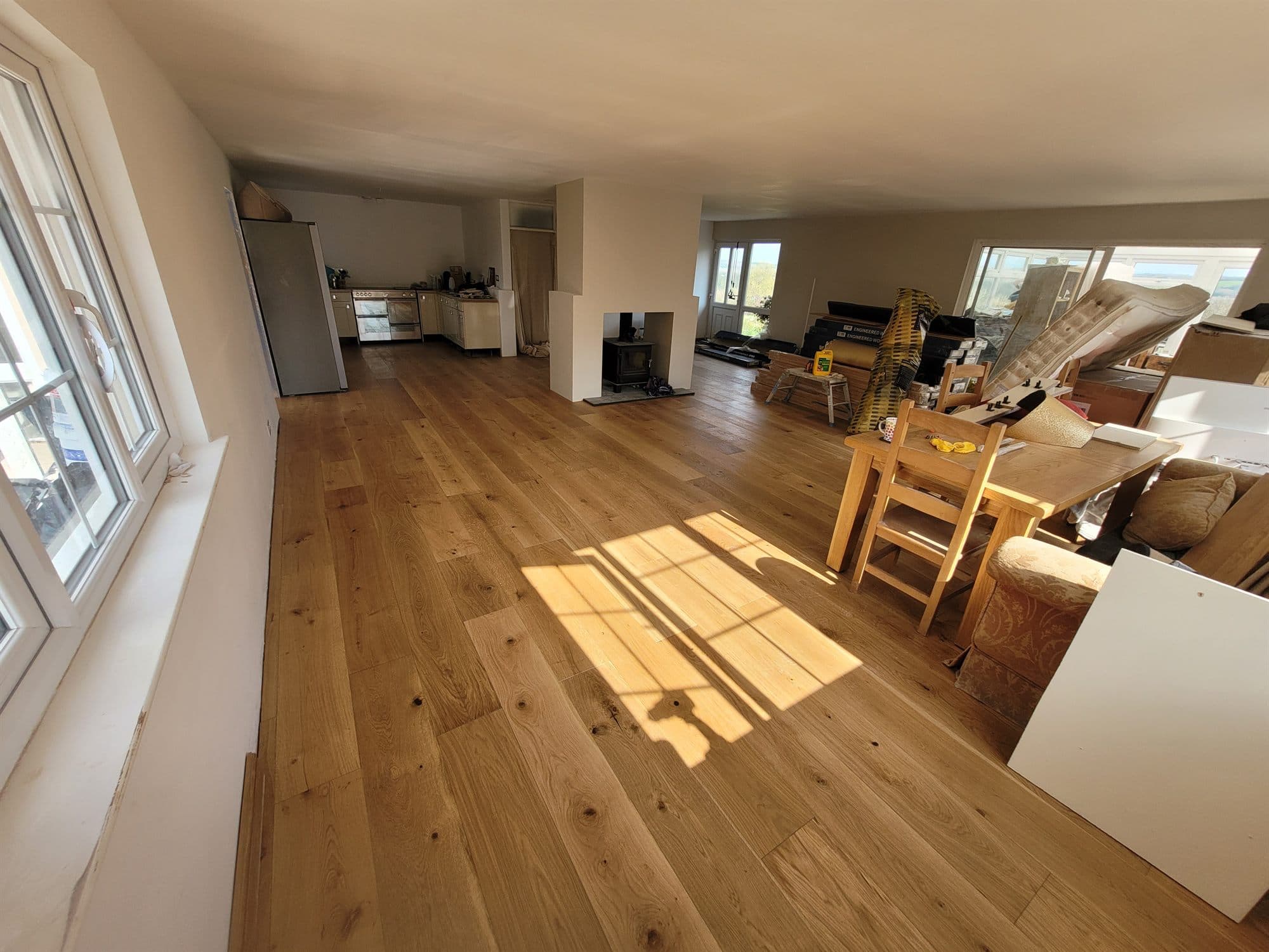 Large open-plan room with newly laid wood flooring in afternoon sunlight