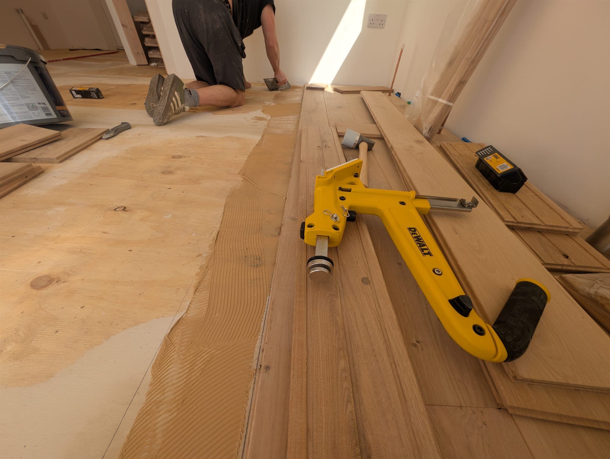 Wood flooring being bonded down with adhesive over a prepared timber subfloor